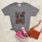 A heather gray graphic t-shirt featuring a colorful autumn floral and pumpkin print, styled in a flat lay with pink high-top sneakers and an orange crossbody bag on a white faux fur background.