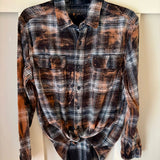 A hand bleach dyed black and rust flannel shirt with a curved hem and buttoned front.