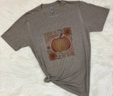Gray t-shirt with pumpkin and sunflower design on a white textured surface